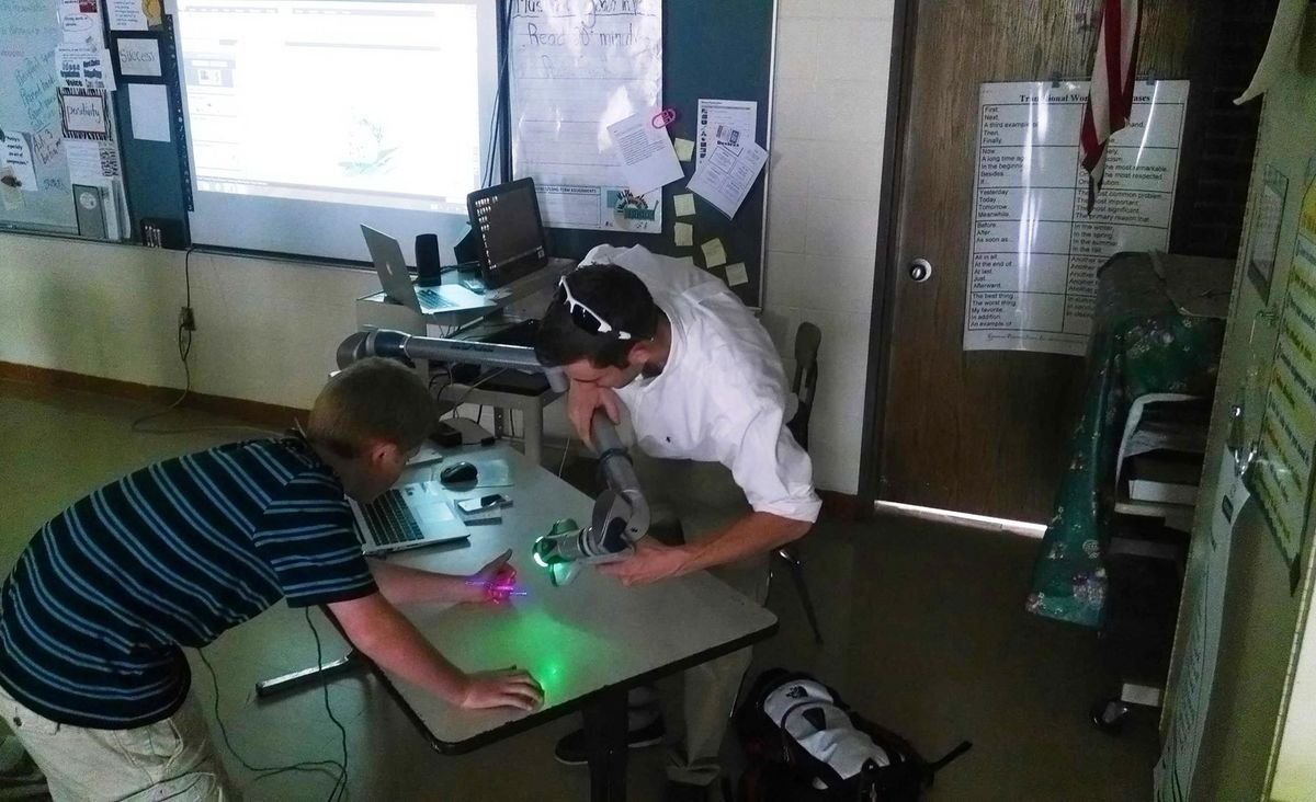 Students using a microscope and measurement equipment during a CMS STEM outreach visit